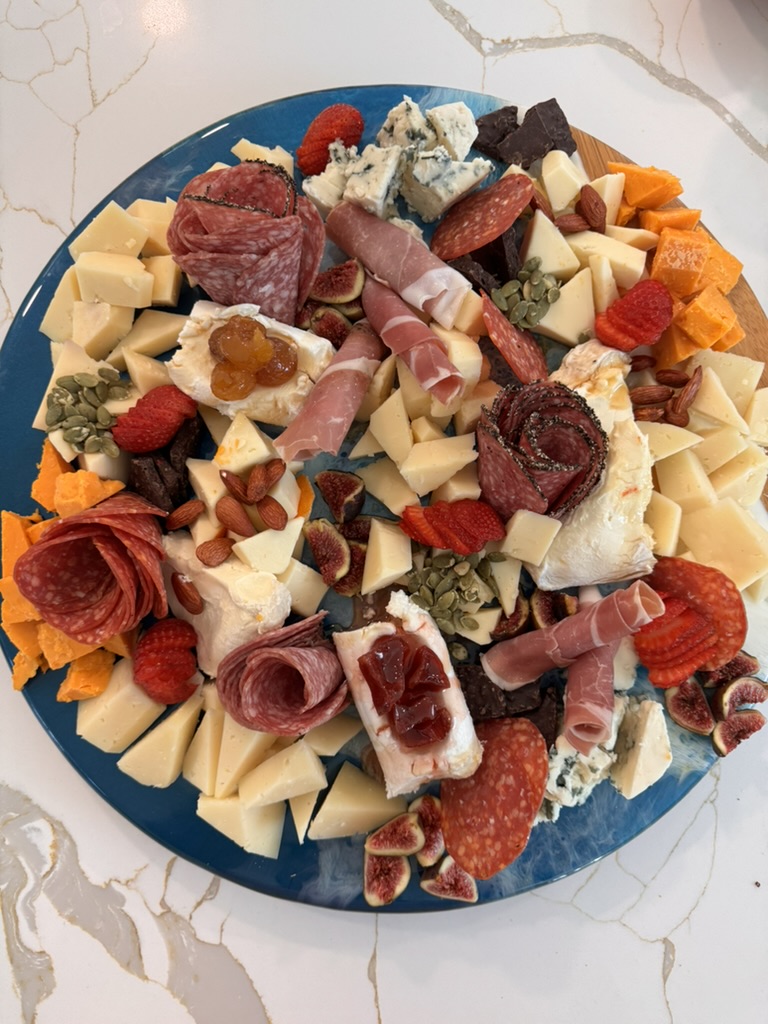 Charcuterie and cheese board with prosciutto, salami roses, aged cheeses, figs, strawberries, almonds and dark chocolate
