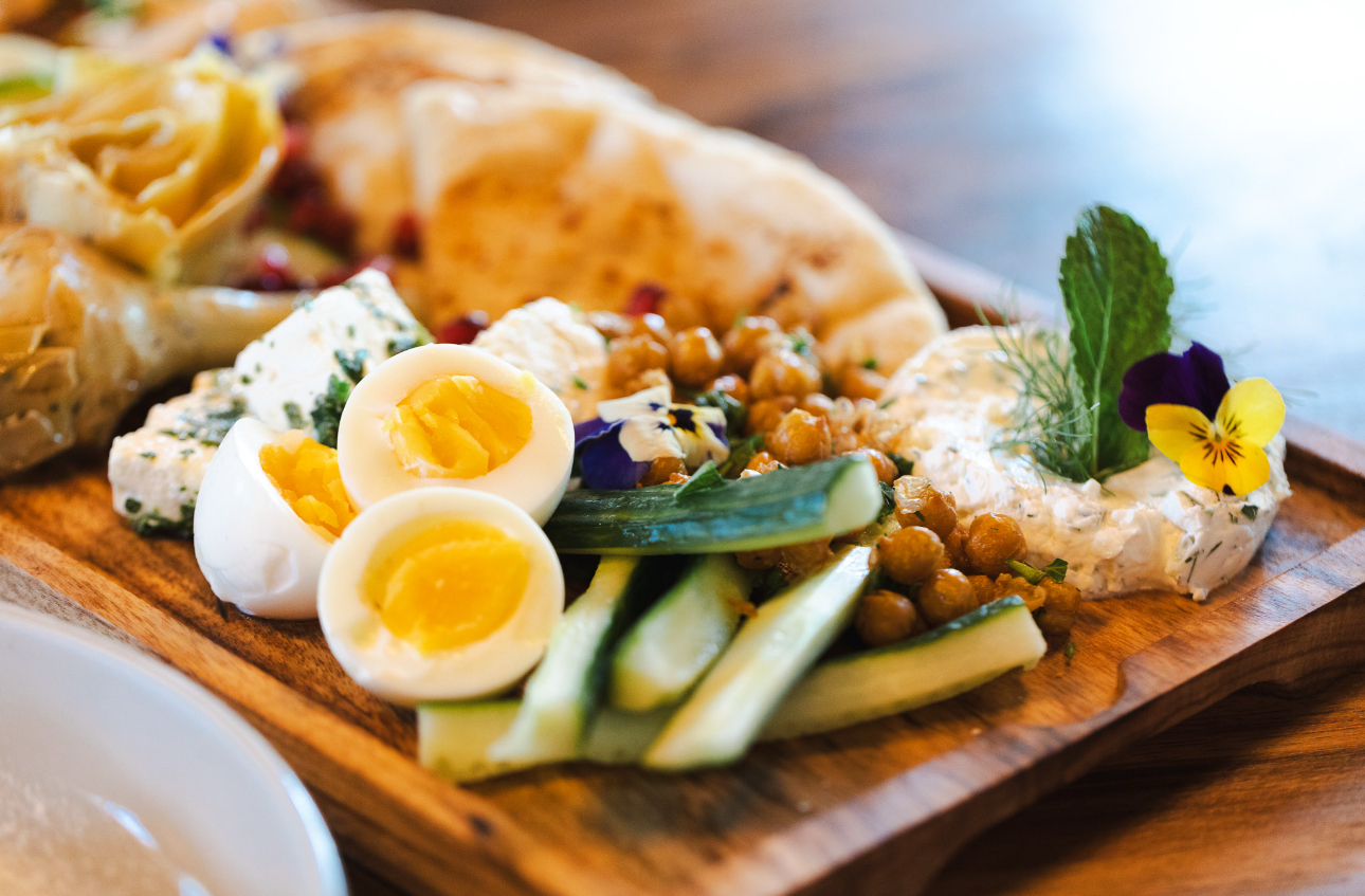 Mediterranean mezze board with soft-boiled eggs, herbed feta, crisp chickpeas, cucumber spears, labneh and warm pita